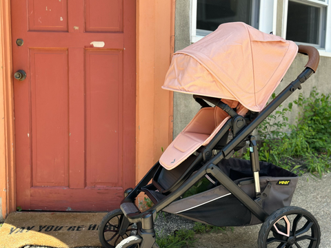 Peachy pink veer &roll stroller parked in front of an equally sweet pink front door to a home