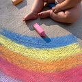 baby sitting next to sidewalk chalk
