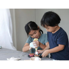 children playing with plan toys cupcake set
